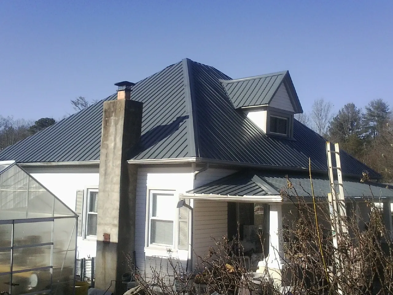 Dark blue standing seam metal roof on a white farmhouse with dormer — Slate & Tile Roof Repair by Roofing Brothers in Corte Madera
