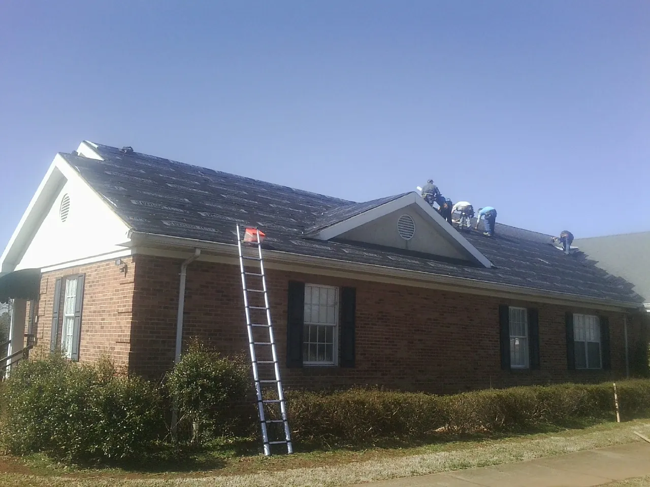 Crew tearing shingles off a brick ranch roof with a ladder set — Metal Roof Repair work by our crew in Corte Madera