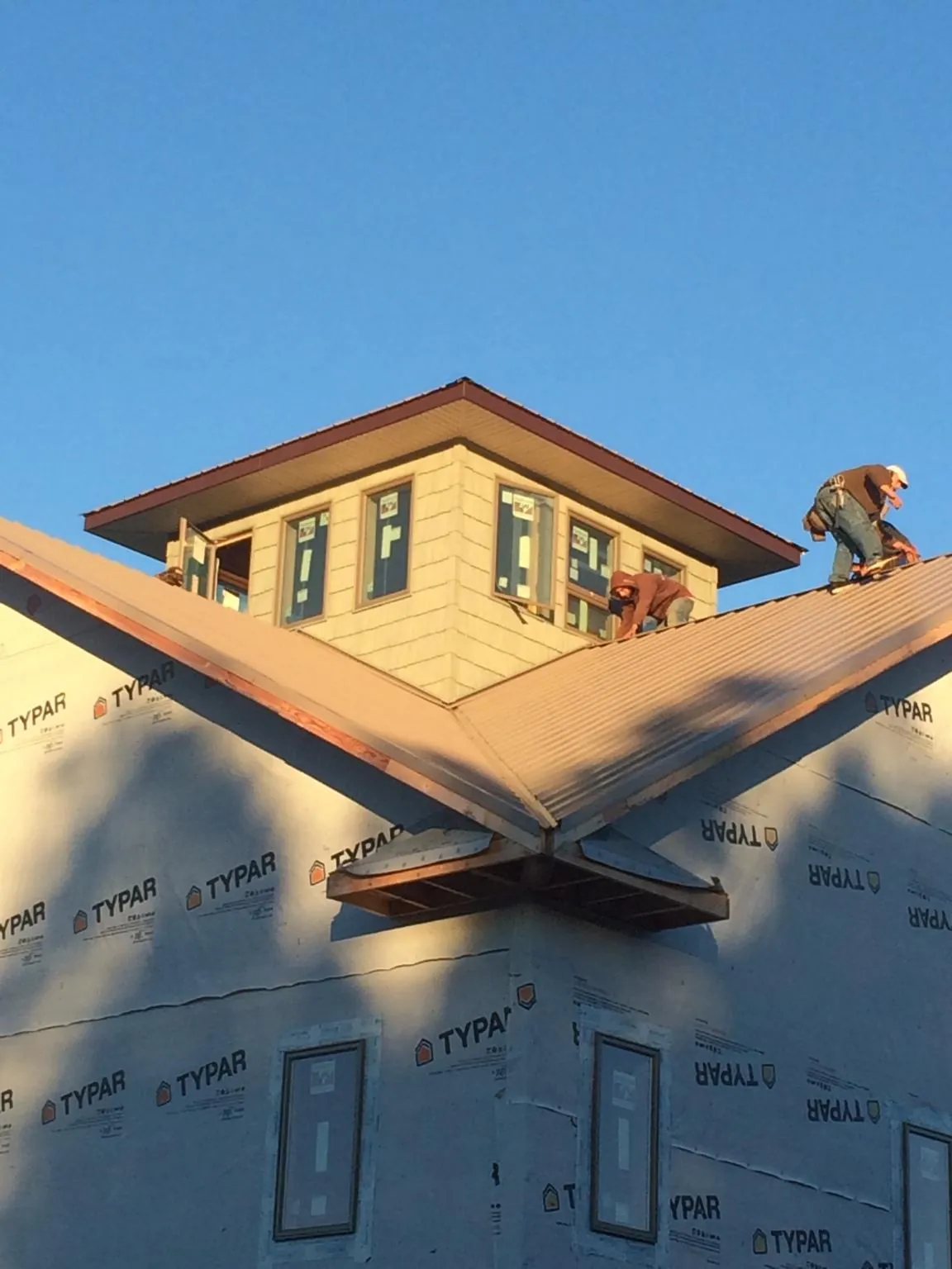 Roofers working around a rooftop cupola on a new metal roof at sunset — Roof Waterproofing in Corte Madera by Roofing Brothers